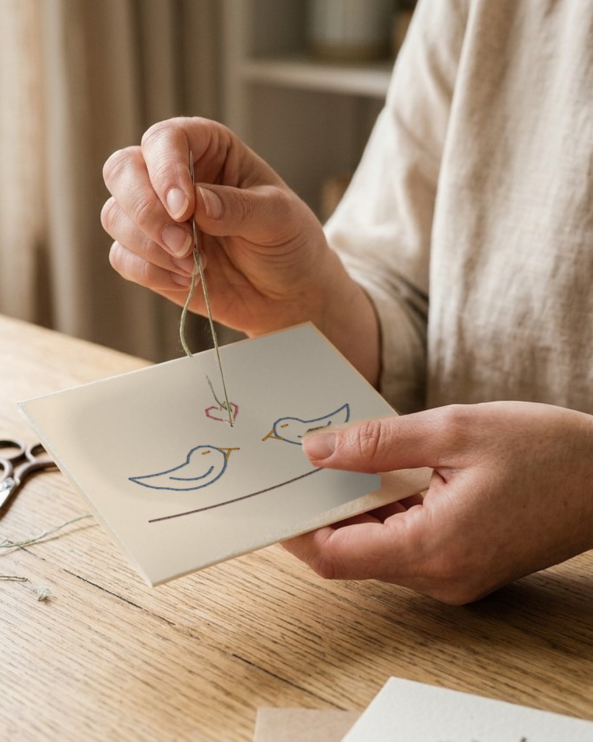 A love birds paper embroidery piece being stitched by hand
